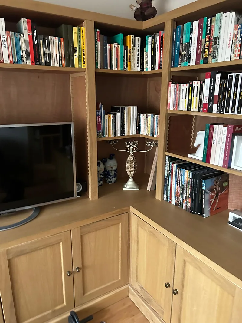 Bibliothèque d'angle en chêne garnie de livres, avec placards bas