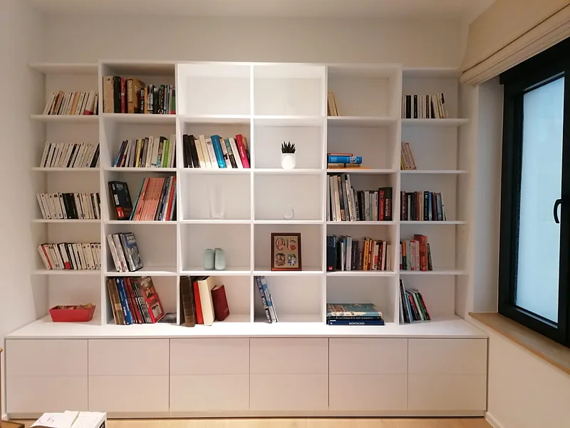 Bibliothèque de salon blanche sur mesure : casiers et meubles bas à tiroirs sur toute la largeur du mur