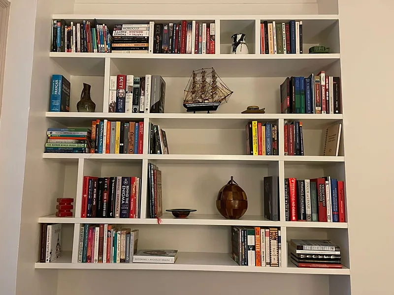Bibliothèque suspendue blanche à cases asymétriques, garnie de livres