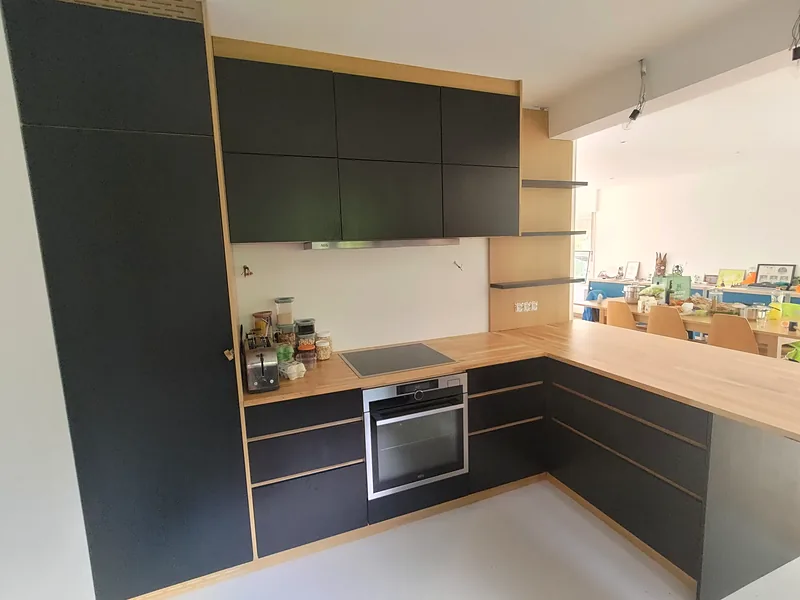 Cuisine d'angle sur mesure en chêne et panneaux noirs, avec four encastré et étagères