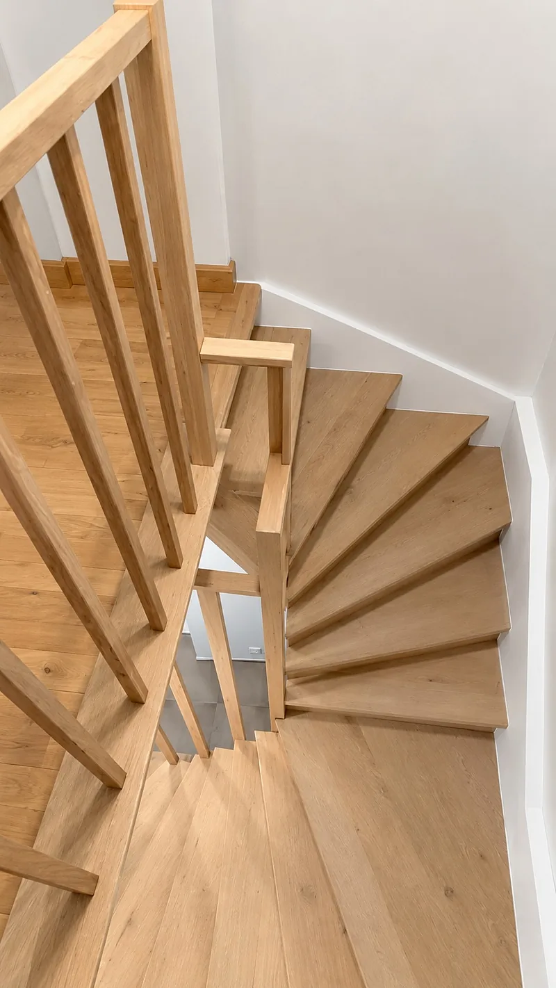 Marches tournantes d'un escalier balancé en bois clair, vues d'en haut