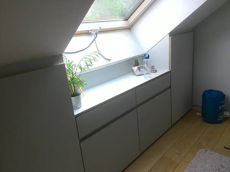 Meuble bas sur mesure sous une fenêtre de toit, avec tablette et tiroirs gris