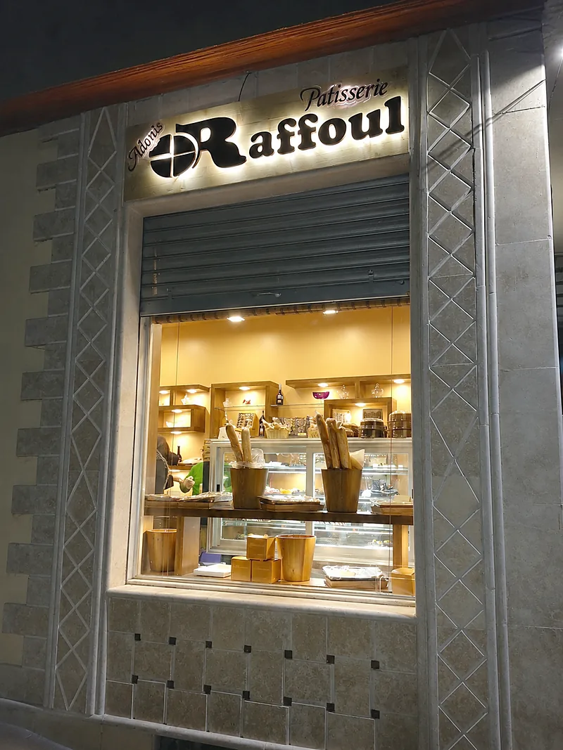 Devanture et vitrine d'une pâtisserie, éclairées de nuit