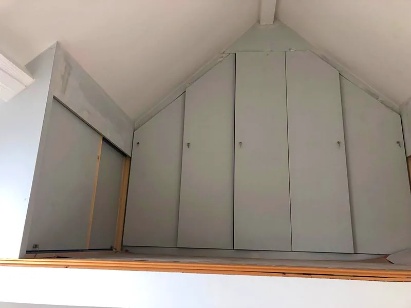 Placards sur mesure sous les combles, portes blanches découpées suivant la pente du toit