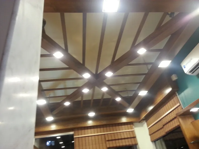 Plafond en bois à poutres rayonnantes avec spots intégrés, dans une pâtisserie