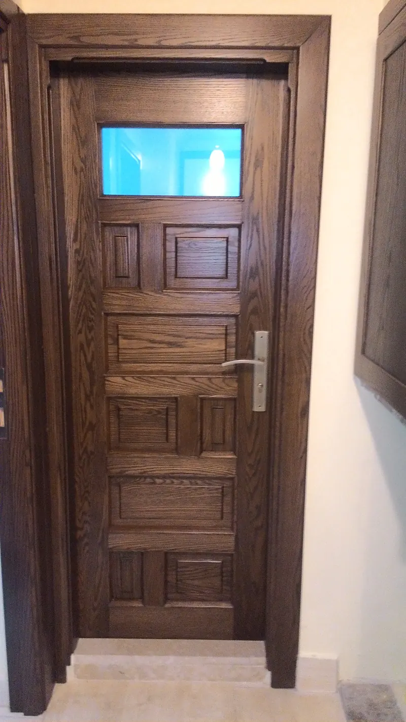 Porte en bois à panneaux moulurés, surmontée d'une imposte vitrée