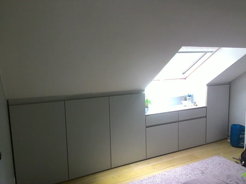 Rangements bas sur mesure sous une pente de toit, façades grises sans poignées