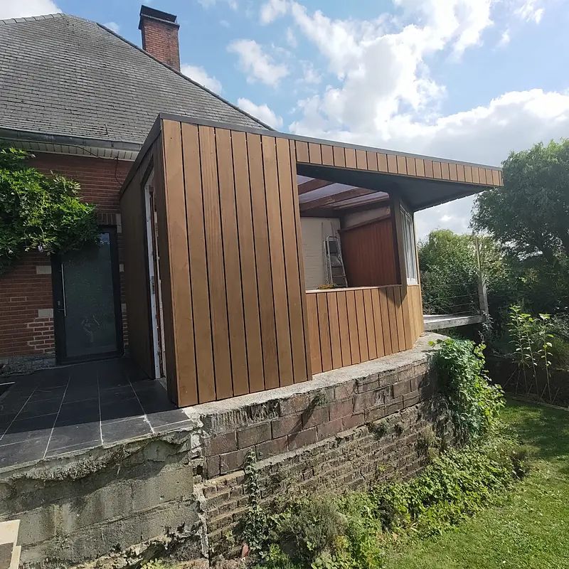 Véranda en bois dont la gouttière est cachée dans la structure