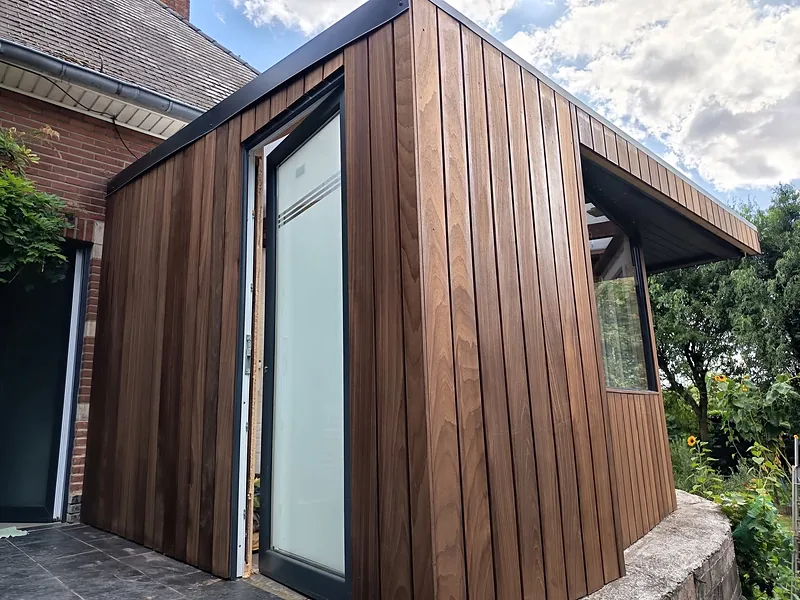 Véranda en bois vue de côté : bardage vertical et porte vitrée